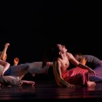 A group of dancers lie on stage in Theta Waves